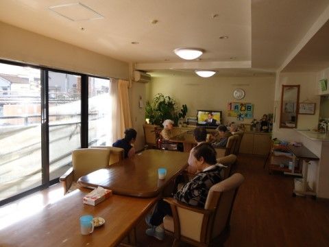 ソファに腰かけて、ダイニングに置かれたテレビを鑑賞している入居者様