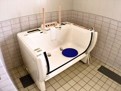 滑り止めマット付きの介護入浴用の浴槽が置かれているタイル貼りの浴室