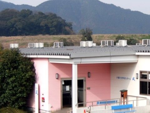 山々に囲まれた施設で、自然を感じながら過ごすことができる。建物の屋根はグレー、壁はピンクとホワイトで存在感がある。