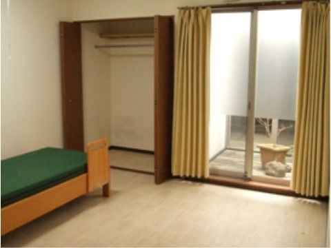 グリーンのベッドが置かれた、落ち着いた雰囲気の居室である。大きな窓のとなりに、収納力のあるクローゼットが完備されている。