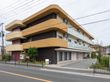 施設はバス通りに面しており、敷地内へ車で入ることができる。オレンジに塗られた屋根の角は丸く面取りがされている。