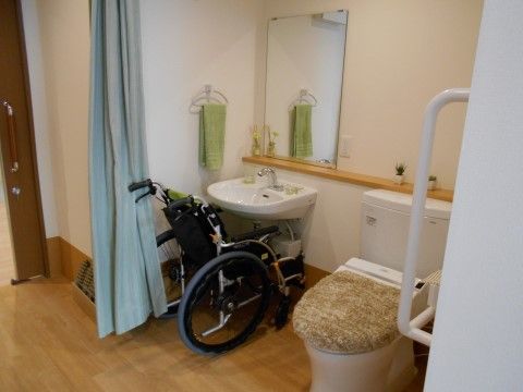 居室内のトイレは車椅子のまま利用できるトイレ、洗面台がある。トイレの横には手すりが取り付けられている。