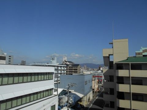 施設５階からの景色。周辺の建物は施設と同程度の高さとなっている。先には標高642mの生駒山が見えている。