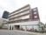 マンションのような外観の施設に、入居者様の募集や内覧会などの案内が掲げられている。建物の周りには植栽がある。