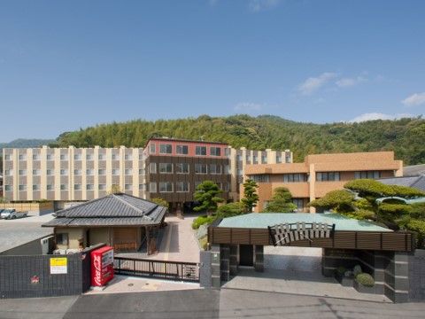 白色、ダークブラウン、ライトブラウンの建物が横に並んで立っている。和風の建物もあり、近くには自動販売機が設置されている。
