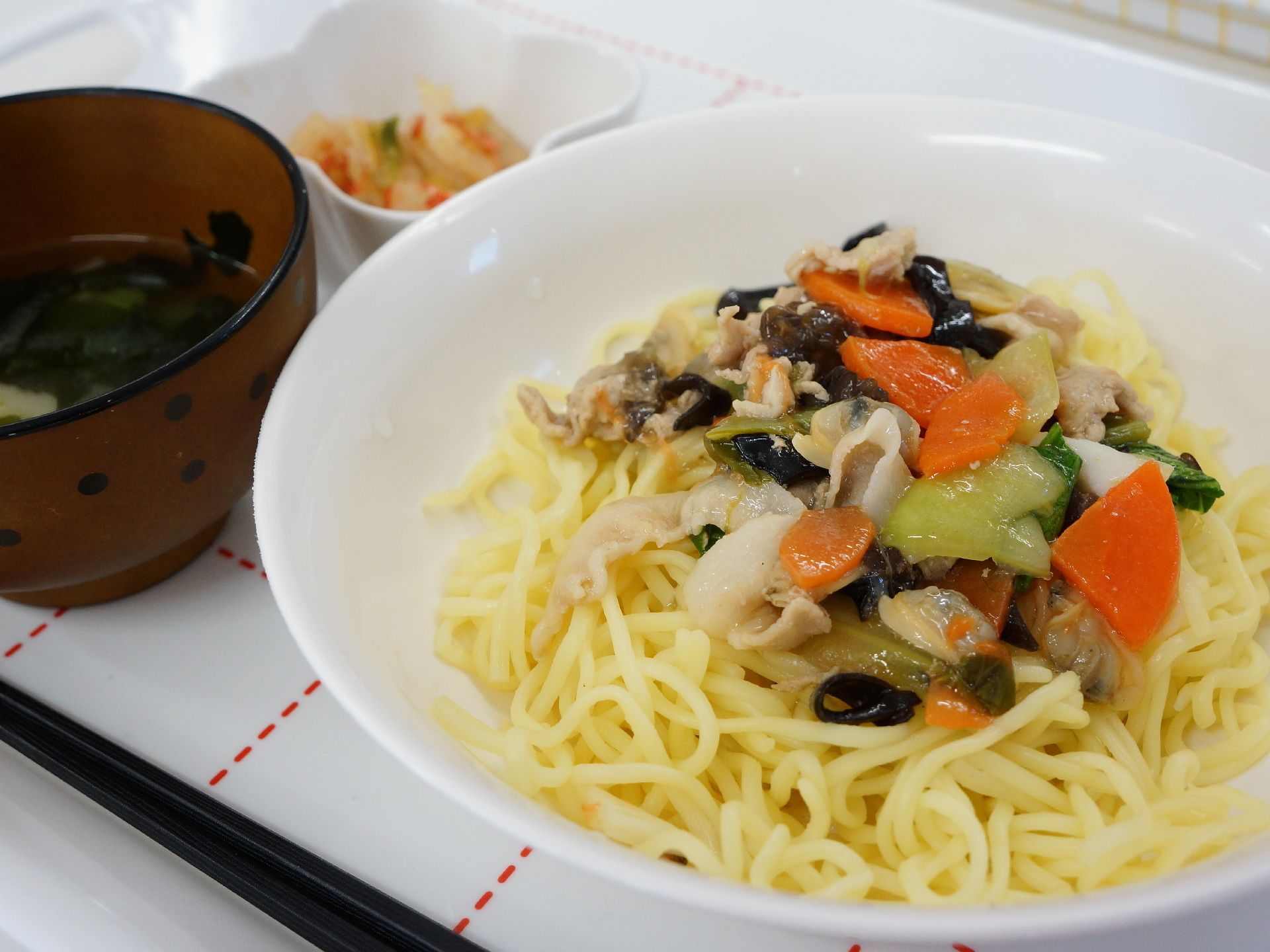 ある日の食事の写真。メニューは野菜たっぷりのあんかけ焼きそばと味噌汁、おかずの小鉢が添えられている。