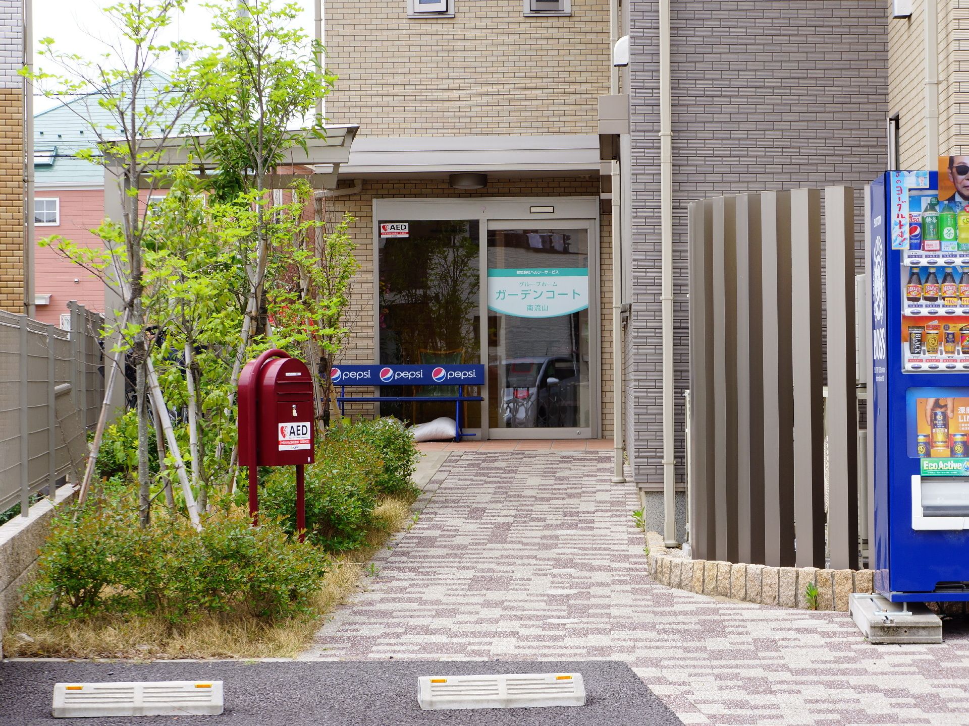 飲料メーカーのロゴが入ったベンチがある自動扉になった玄関