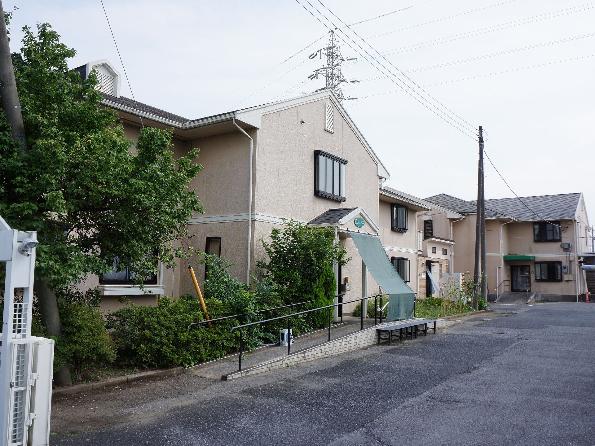 アコーディオンゲートで囲まれた敷地の中は、アスファルトで舗装してあり、駐車場がある。建物の周囲は植栽してある。