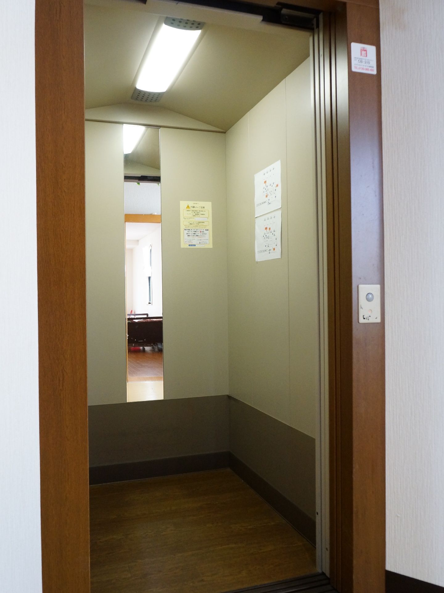 エレベーター内は幅も奥行きもあり、車椅子ご利用の方にも快適にご利用になれる。照明と鏡が設置されている。