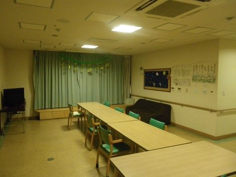 ベージュとグリーンで統一された空間である。壁には手すりを取り付けてあり、入居者様の作品を展示している。