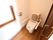 大きな引き戸のトイレの扉である。床はフローリングになっている。手すりや背もたれが付いている。車椅子でも使用しやすい。