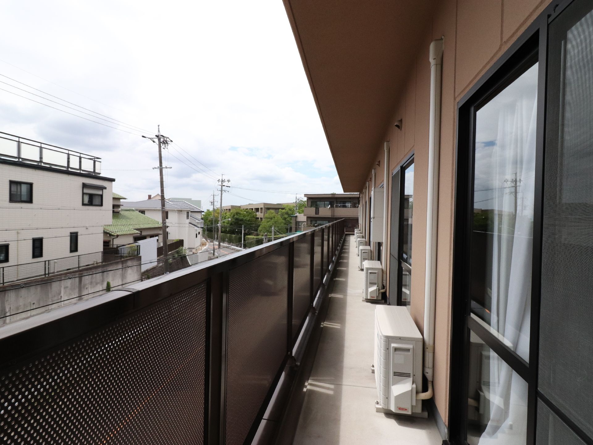 エアコンの室外機が置いてある。隣との隔たりがないベランダである。非常時に逃げやすいよう、考慮されている。