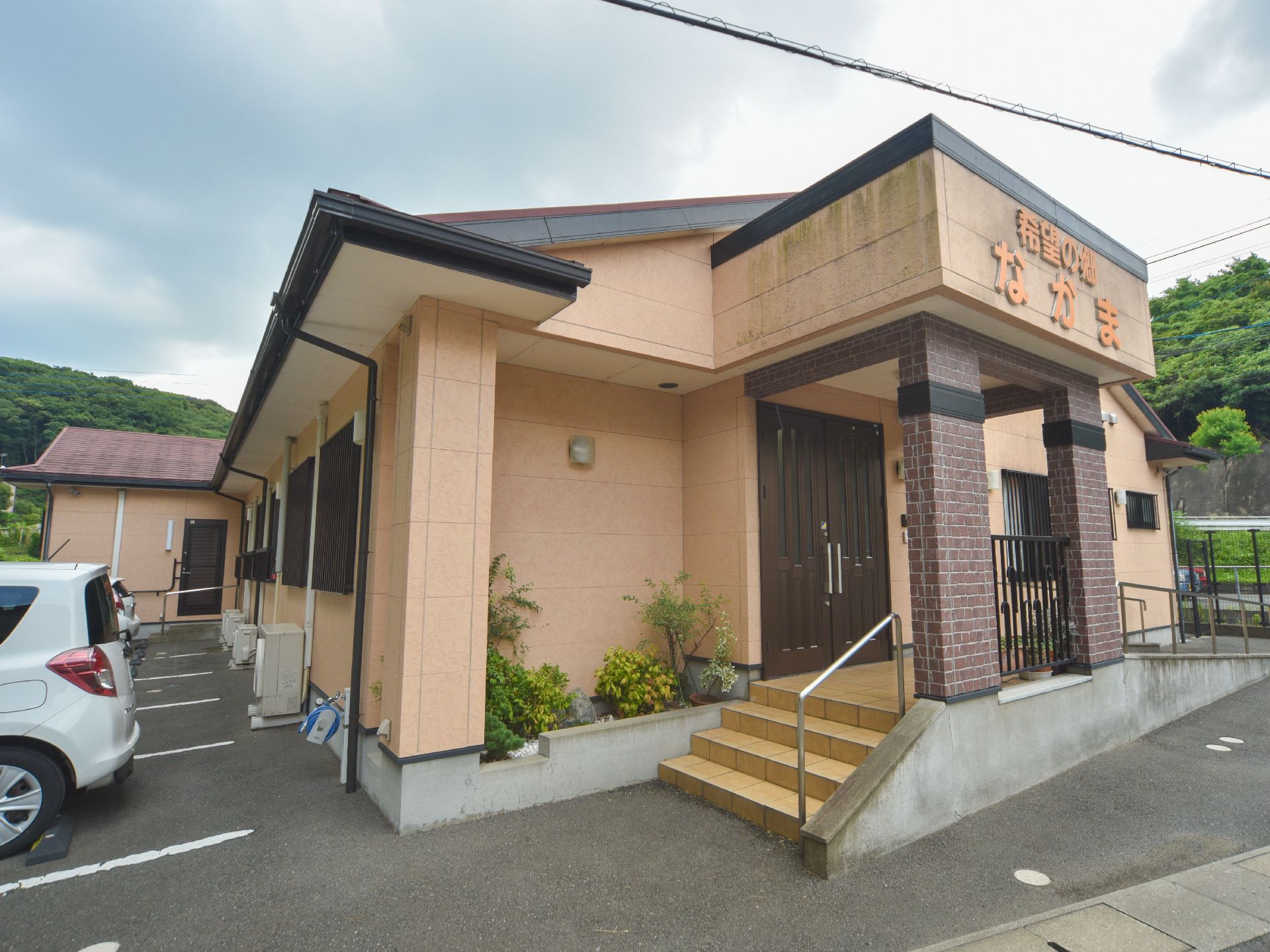 施設の入り口部分には小さな和風の坪庭を完備。周囲に民家はなく静かな場所に立地している。一般家庭のような玄関の扉になっている。