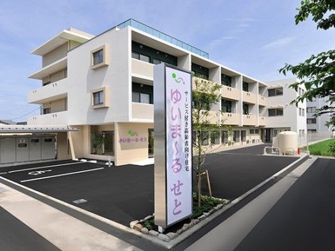 ピンクの字で施設名称が書かれた看板が立っている外観