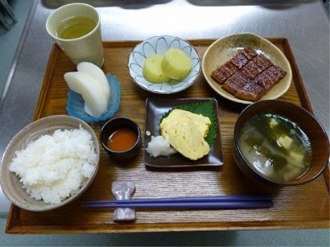 木製の四角いトレイに卵焼きやうなぎが配膳されている食事