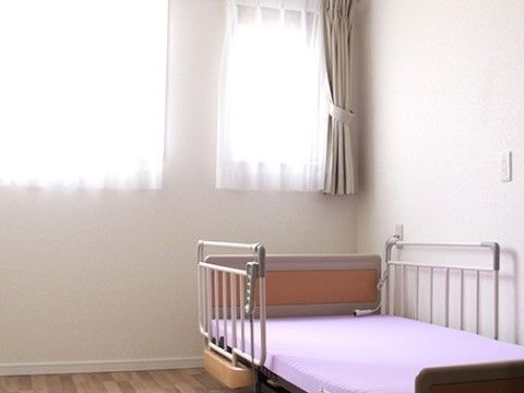 薄手のカーテンが閉められた窓の前に置かれている介護用ベッド
