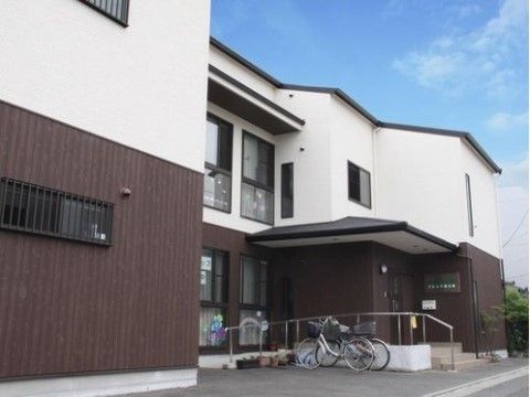 入口前のスロープ横に自転車が２台停まっている施設外観