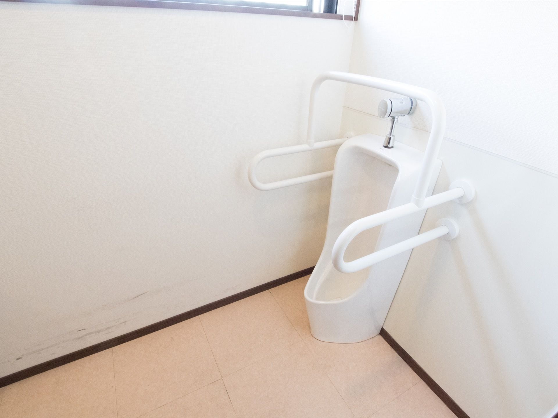 トイレの小便器の両側には専用の安全バーを設置している。入居者様がトイレをご利用時に不意な転倒を防止することができる。