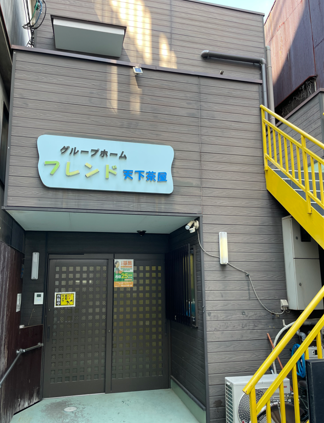 施設名が書かれた看板の下で格子状の入口扉が閉まっている玄関ポーチ