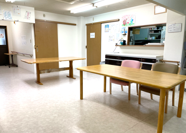 木製のテーブルの周りに集まって、会話を楽しむスタッフと入居者様
