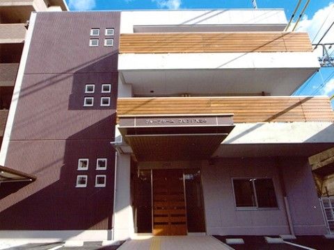 ２階のベランダ部分が入口前の屋根になっている３階建ての建物