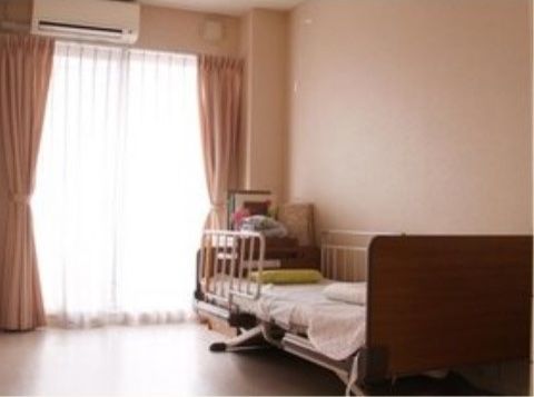カーテンの開いた窓の上にエアコンが取り付けられている居室