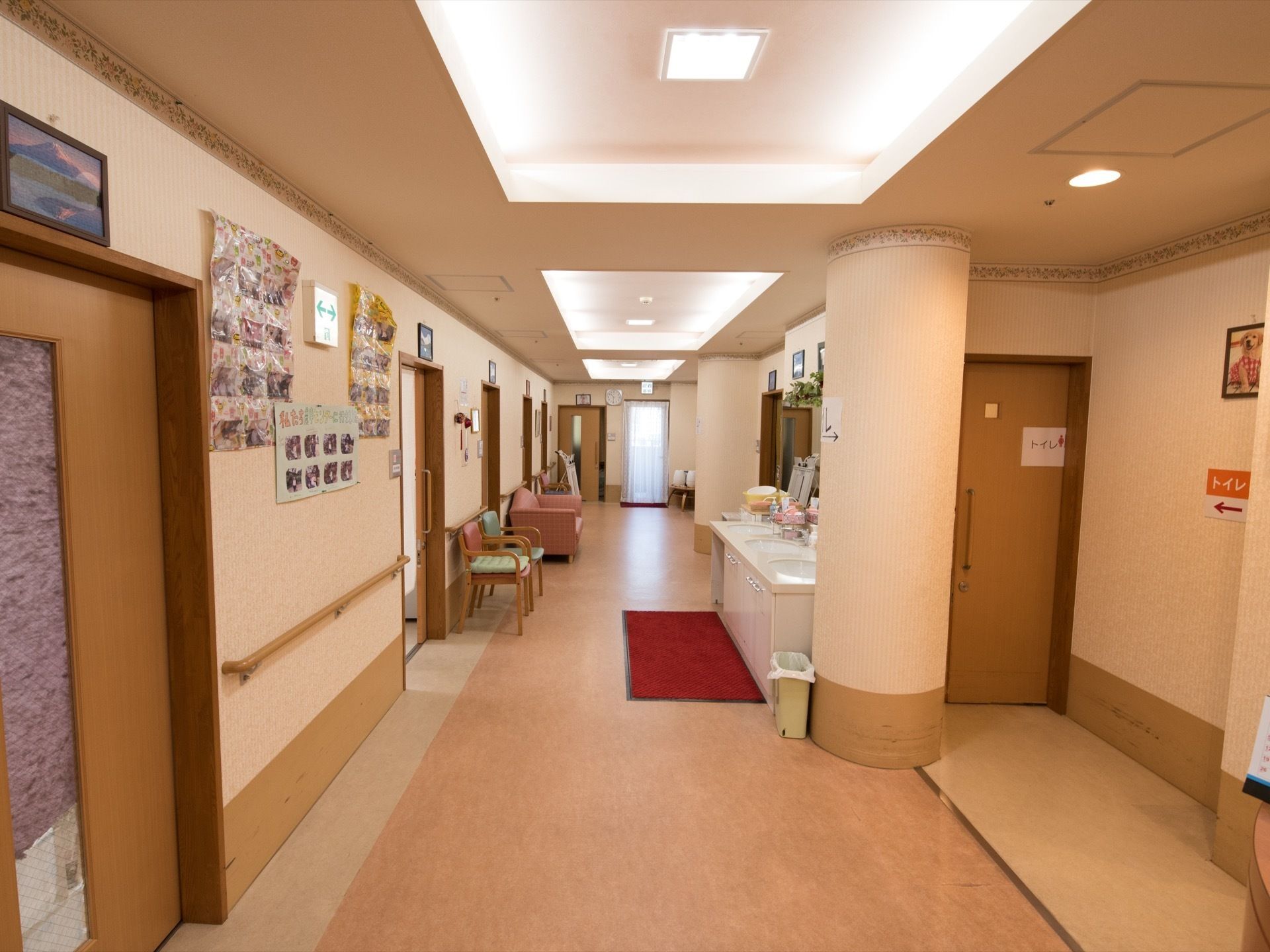 居室のドアが並ぶ廊下である。ドアの上には絵を飾り、壁には、写真などを貼っている。３台の洗面ボールが並ぶ洗面台を設置している。