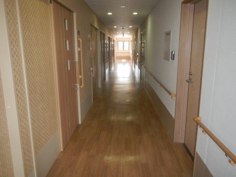 明るい通路には手すりが続き、居室の脇にも大きな手すりがある。天井のダウンライトの間にはスプリンクラーやセンサーが設置されている。