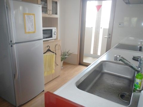共同で使える明るいキッチンには、電子レンジや大型冷蔵庫がある。広いシンクの横には、IHがついたキッチンセットも備えている。