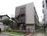 ブラウン色の建物。上部にオレンジ色で施設名が書かれている。入り口前には立て看板と傘立てが置かれている。