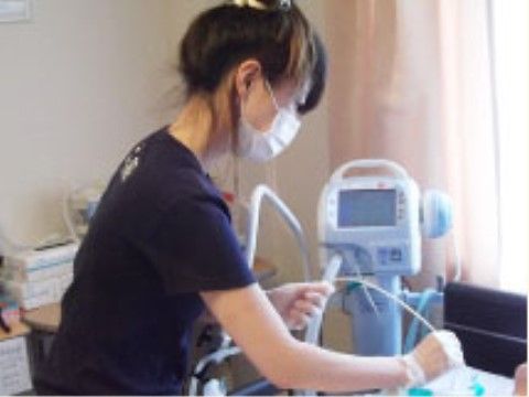 ベッドに横になった入居者様に機械を使って診療をするスタッフ