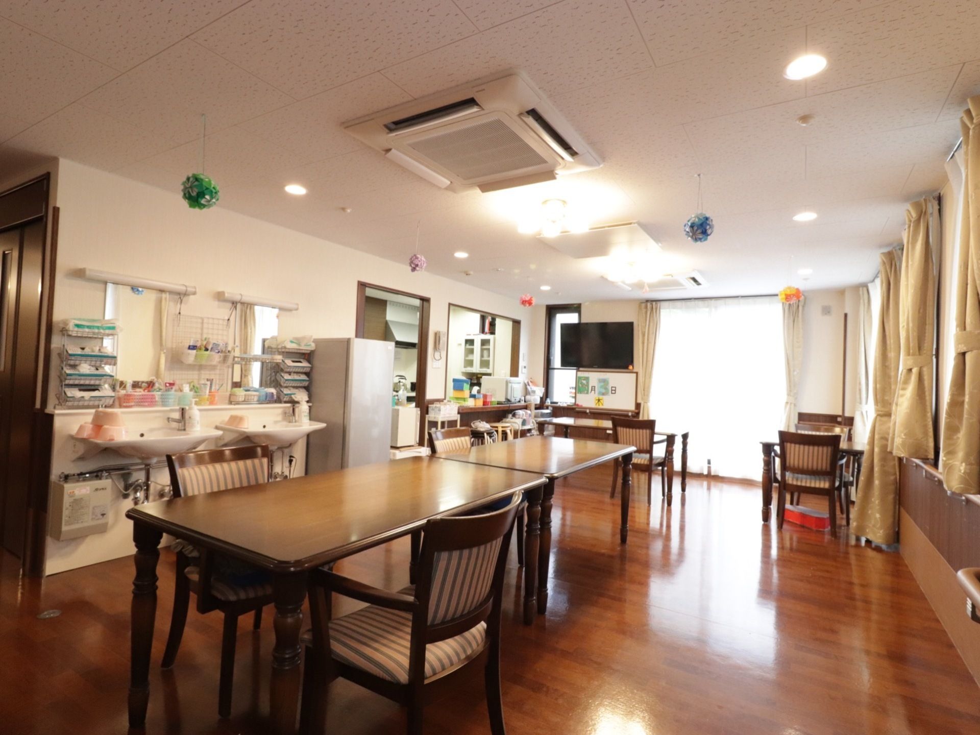 窓から日差しが入り、明るい室内である。天井には飾りがある。1人当りのテーブル面積が広い。テレビ、冷蔵庫が設置されている。手洗い所もある。