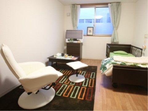 赤やオレンジの四角がデザインされたラグが敷かれている居室