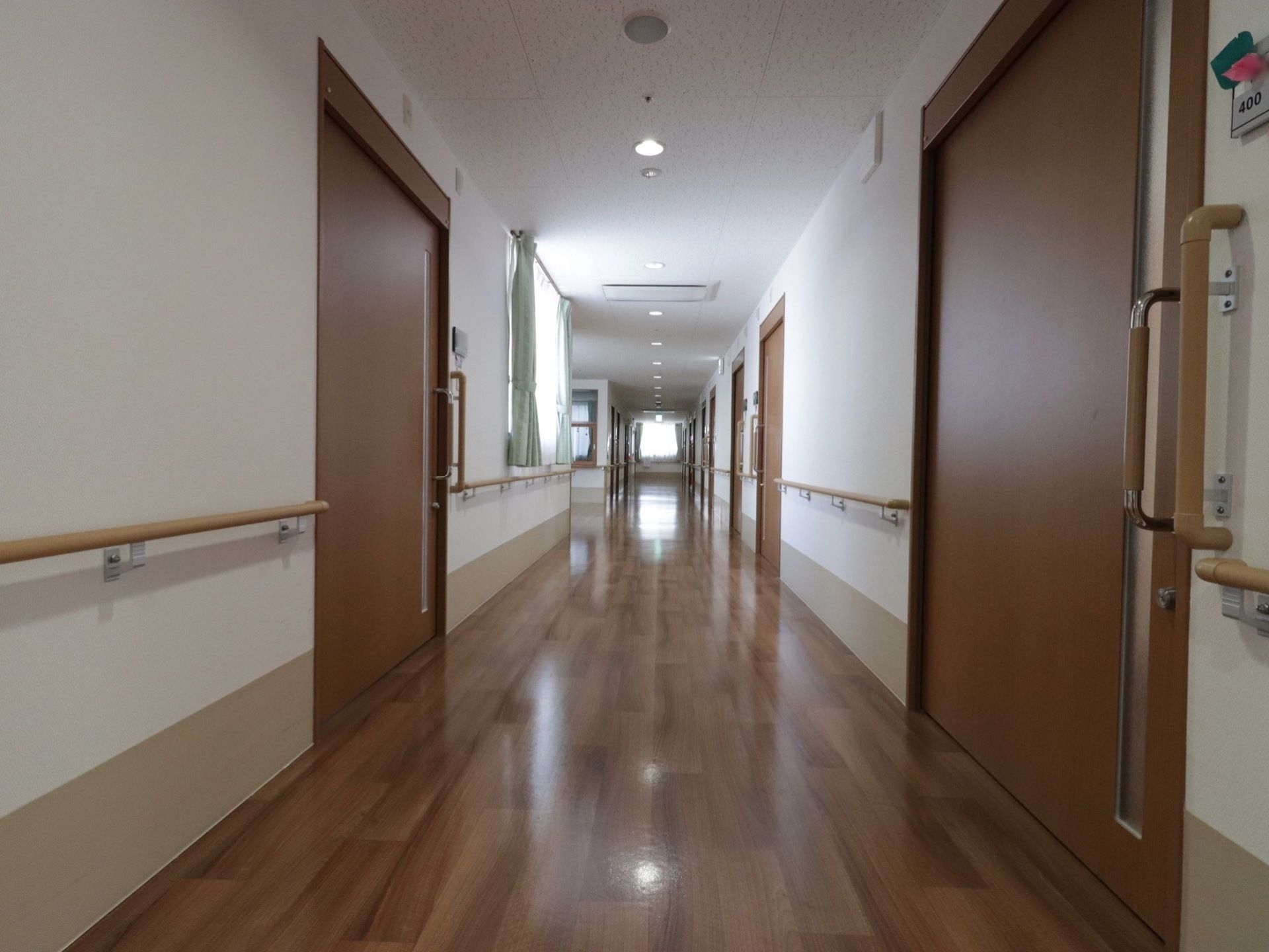 廊下にはいくつかの扉が設置されており、窓にはカーテンも取り付けられている。手すりも壁と扉の近くに設置されている。