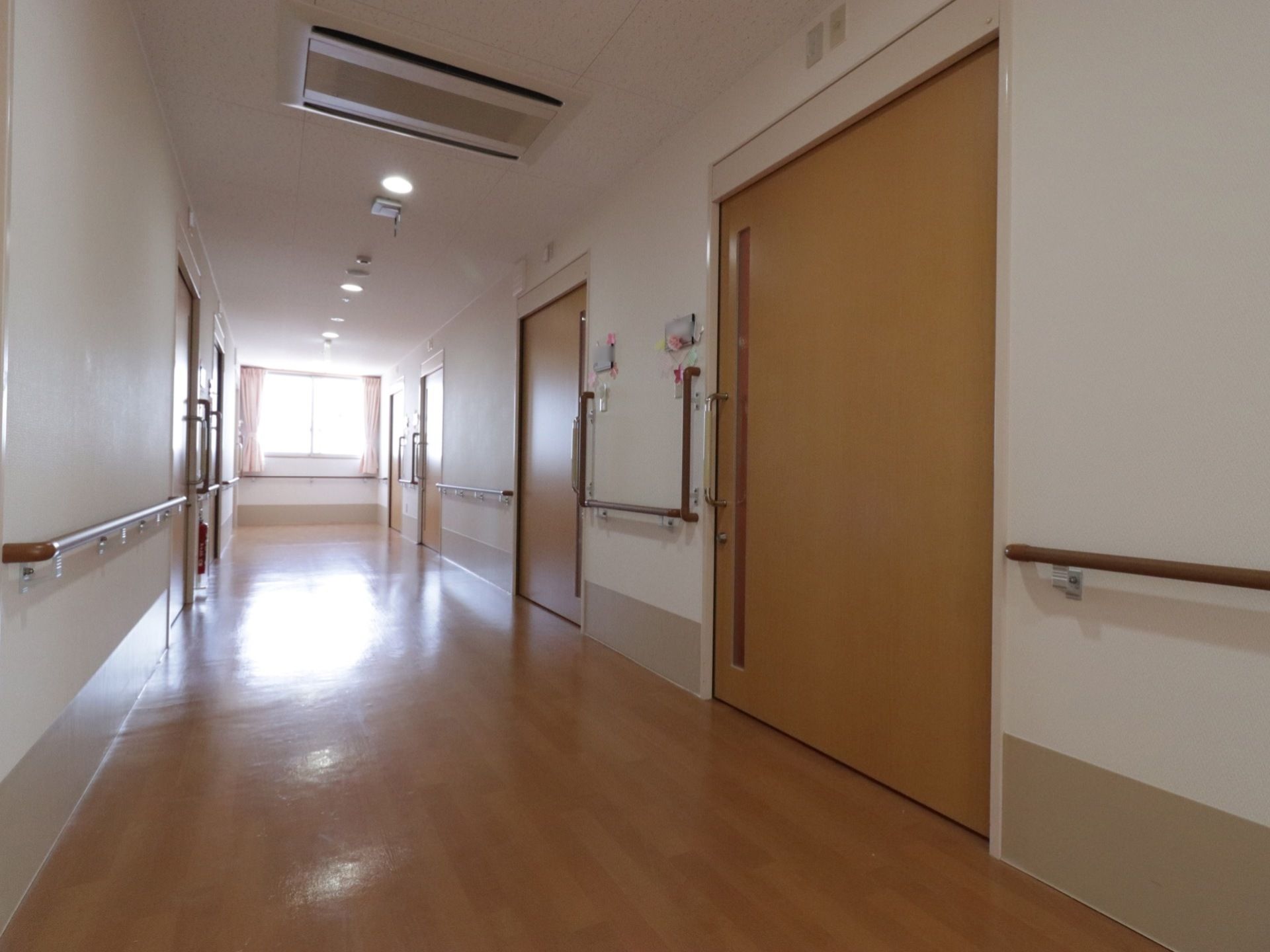 通路は広く、両側の壁に手すりが付いている。居室のドアは大きくて、引き戸になっている。突き当りには窓があり、明るい光が入ってくる。