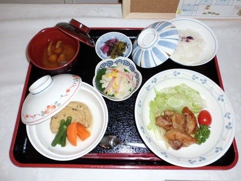 蓋つきの椀に盛りつけられた煮物や、鳥の照り焼きが置かれたトレイ