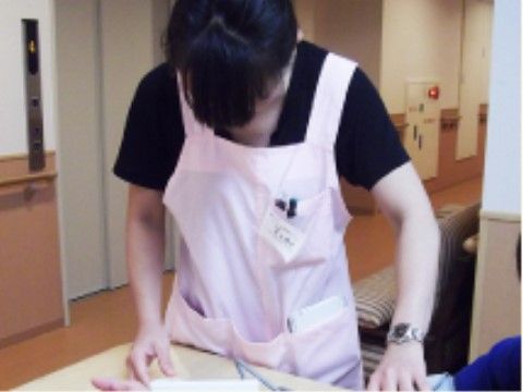 入居者様の腕に血圧計のベルトを巻いている女性スタッフ
