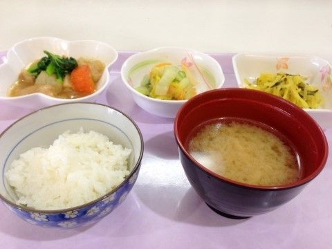 薄紫色のお盆の上に食事が配膳されている。ごはん、お味噌汁、お漬物のほか、野菜を使ったおかず２品である。