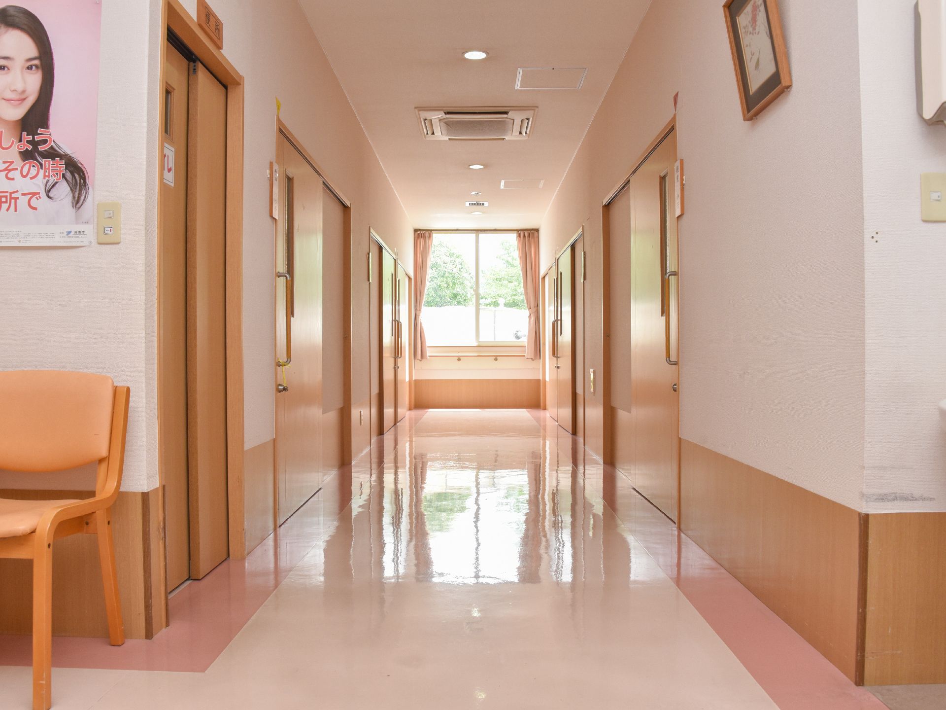 両側に居室やトイレへ続く入口扉が並んでいるタイル貼りの廊下