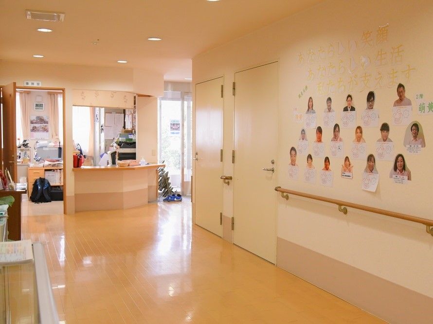 壁にスタッフの顔写真と自己紹介文が掲示されている廊下