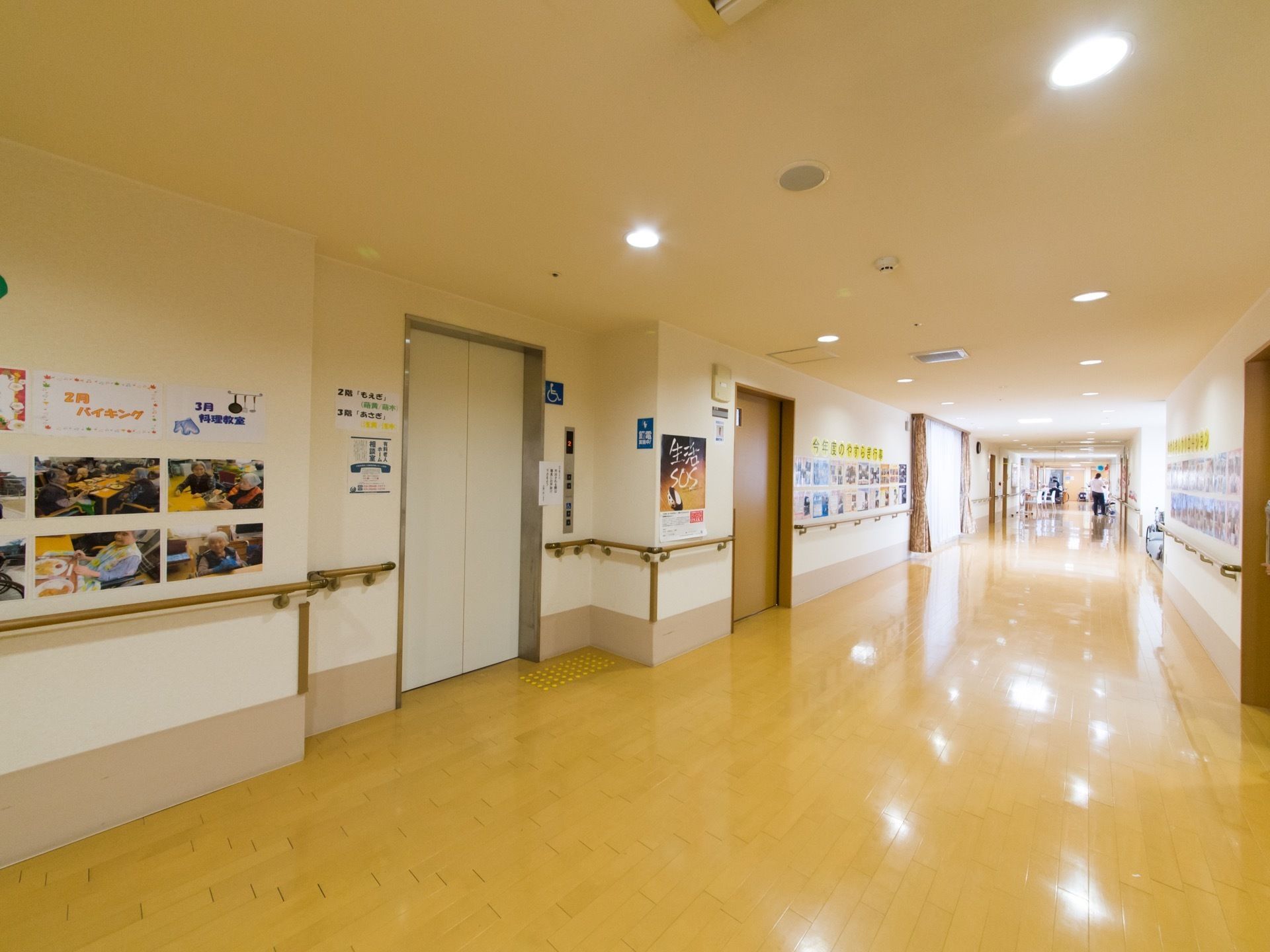 廊下の壁に施設で行われた行事、イベント写真が貼り出されている。面会に来る家族などが一目で施設での生活が分かるようになっている。