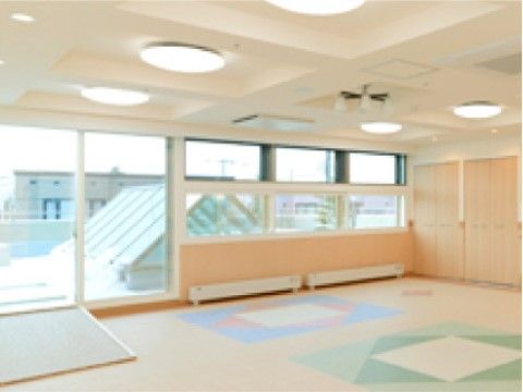 ナチュラルな色合いの床には、テラス外へのスロープが設置されている。壁一面の窓からは明るい光が取り入れられている。