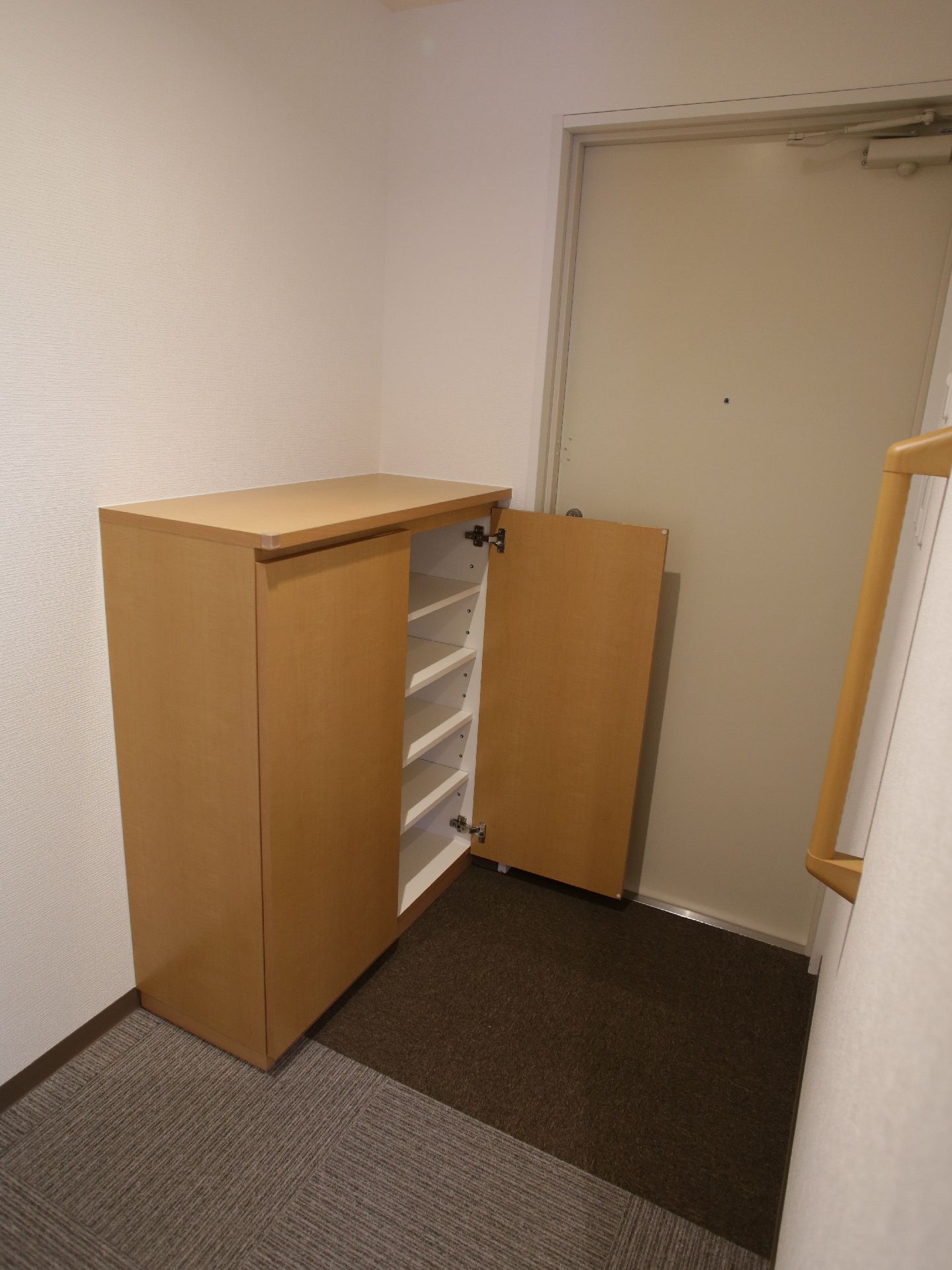 部屋の入り口にはカーペットが敷かれ、下駄箱が設置されています。扉は両開きで、内部には移動可能な棚が5段あります。
