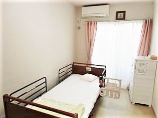 大きな窓があり明るい雰囲気。居室には、ベッドやタンスだけでなくエアコンもついている。