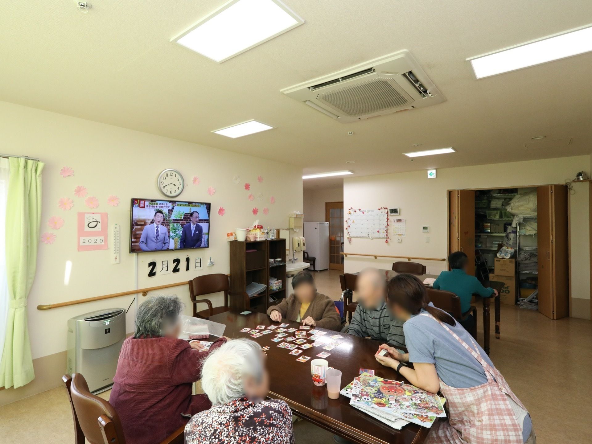 リビングのテーブルでスタッフとカードゲームを楽しむ入居者