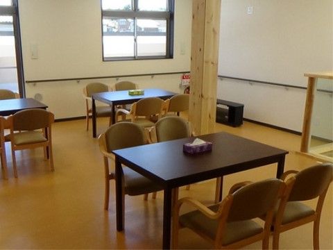 白の壁紙を基調としたリビングには、木製のテーブルや椅子が並んでいる。大きな窓からは光が差し込み、明るい室内となっている。