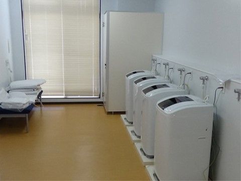 白い壁紙で清潔感のある洗濯室には、複数台の洗濯機を備えつけている。大きな窓からの光が差し込みとても明るい空間。