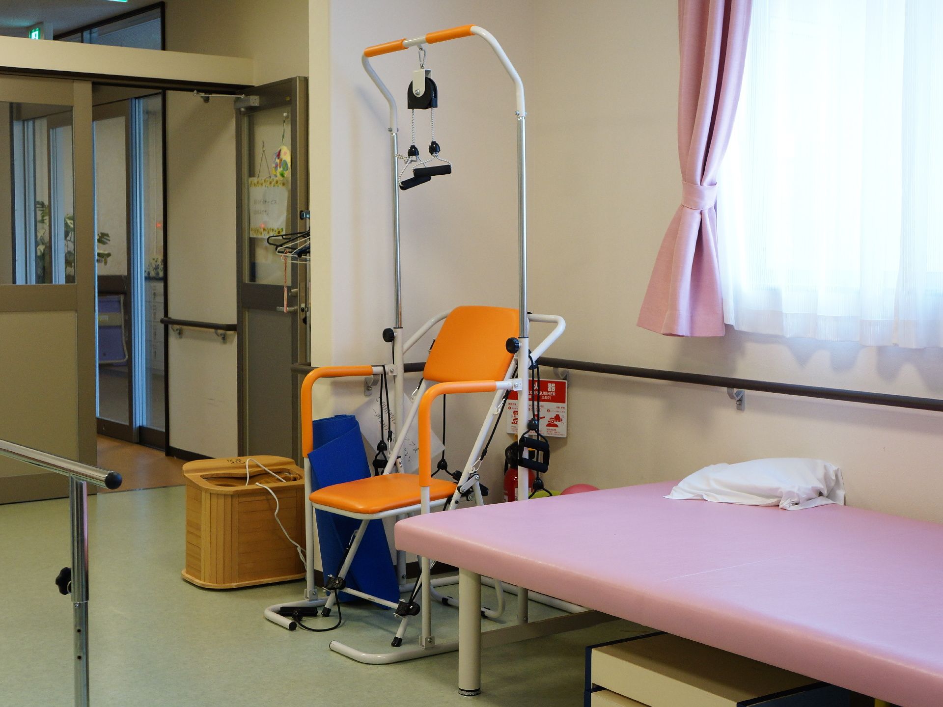 訓練室にある筋トレ用の機械と、簡易ベッドが入り口付近に設置されています。座ったまま筋トレができる機械です。