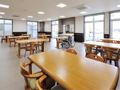 窓が広く採光も十分で開放感がある。木製のテーブルセットが設置されている。通路も広く取られていて移動しやすい。