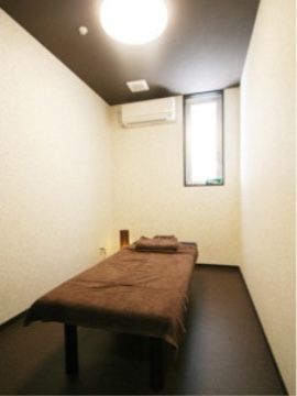 床面はフローリング、壁面は白が基調の落ち着いた雰囲気で、マッサージ用ベッドが設置されている。エアコンも完備している。